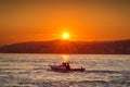 A small boat floats on the sea against the backdrop of the rising sun. Royalty Free Stock Photo